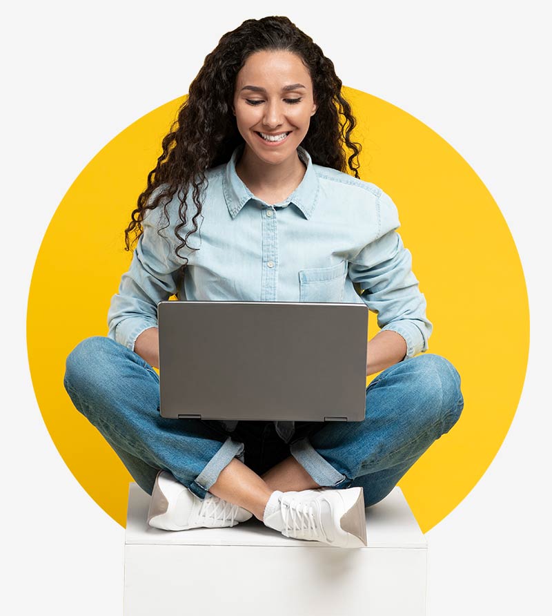 A woman sits cross-legged and looks at her laptop - she is pleased with the selection of CRM industry solutions from awisto and the many Dynamics 365 CE reference customers.