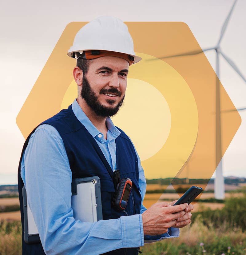 The picture shows an employee in front of wind turbines. He is using Dynamics 365 Field Service on his smartphone.