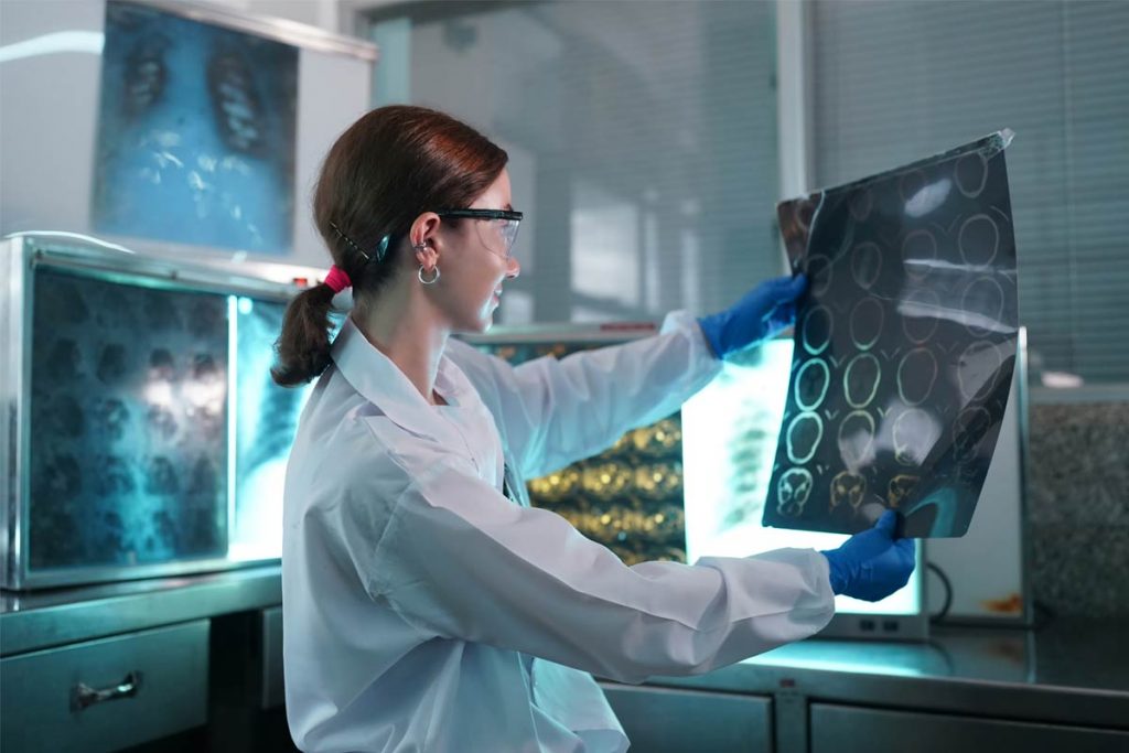 The picture shows a seated doctor evaluating X-ray images. The image symbolizes the awisto CRM medical technology industry solution.