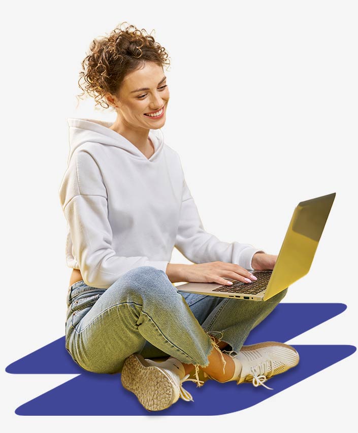 Young woman sitting cross-legged working on her laptop. She is happy about the portal integration with Power Pages.