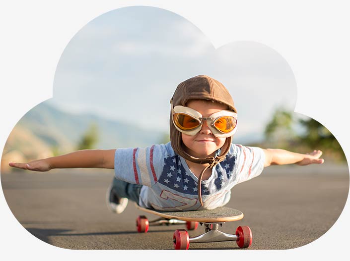 A boy with aviator goggles is lying on his stomach on his skateboard with his arms outstretched to the side. As if he were flying. He symbolizes our vision for digitalization.